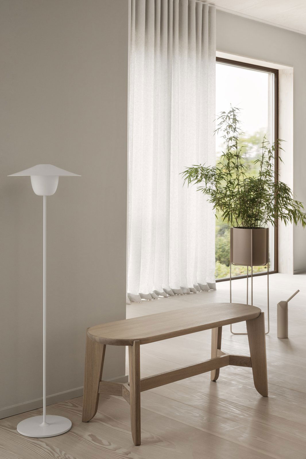 Modern living room with a white floor lamp, bamboo plant, and light curtains.