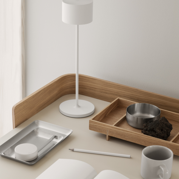 Minimalistischer Schreibtisch mit einer Lampe, Tabletts, einer Tasse und einem dekorativen Stein.