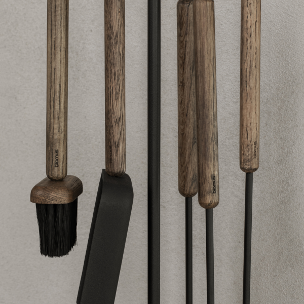 Stylish kitchen utensils with wooden handles displayed against a textured wall.