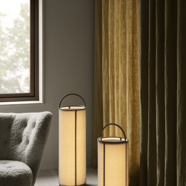 Moderne Stehlampen neben einem gemütlichen Sessel und eleganten Vorhängen in einem schicken Innenraum.