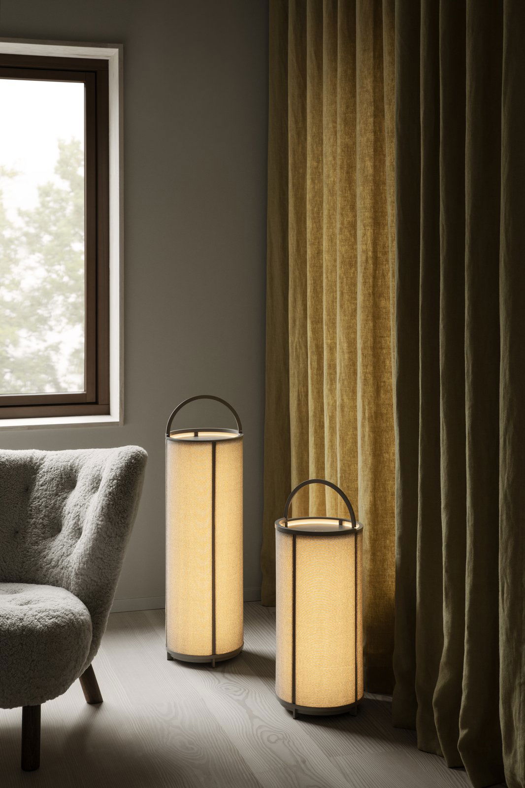 Moderne Stehlampen neben einem gemütlichen Sessel und eleganten Vorhängen in einem schicken Innenraum.