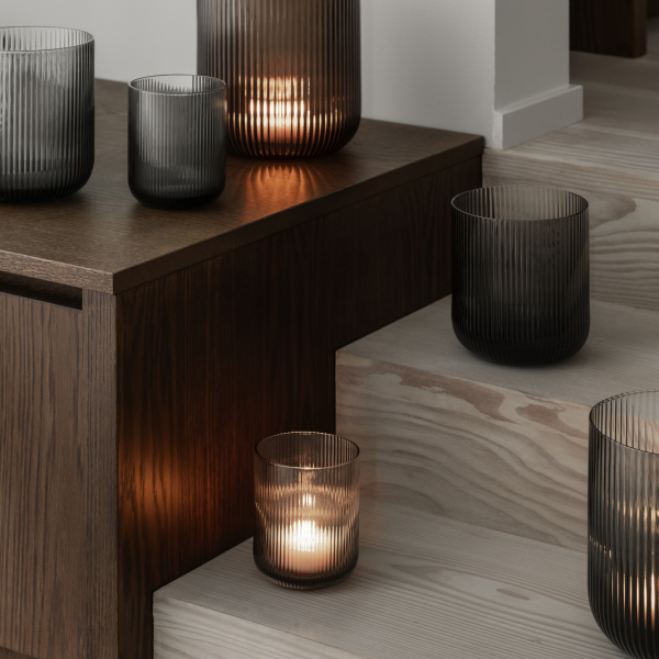"Elegant glass candles casting warm light on wooden steps and furniture."
