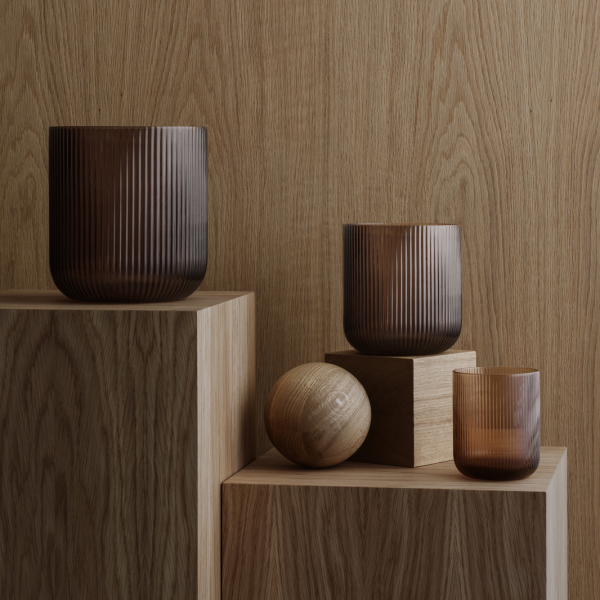 Stylish brown glass vases and wooden spheres on textured wooden blocks.