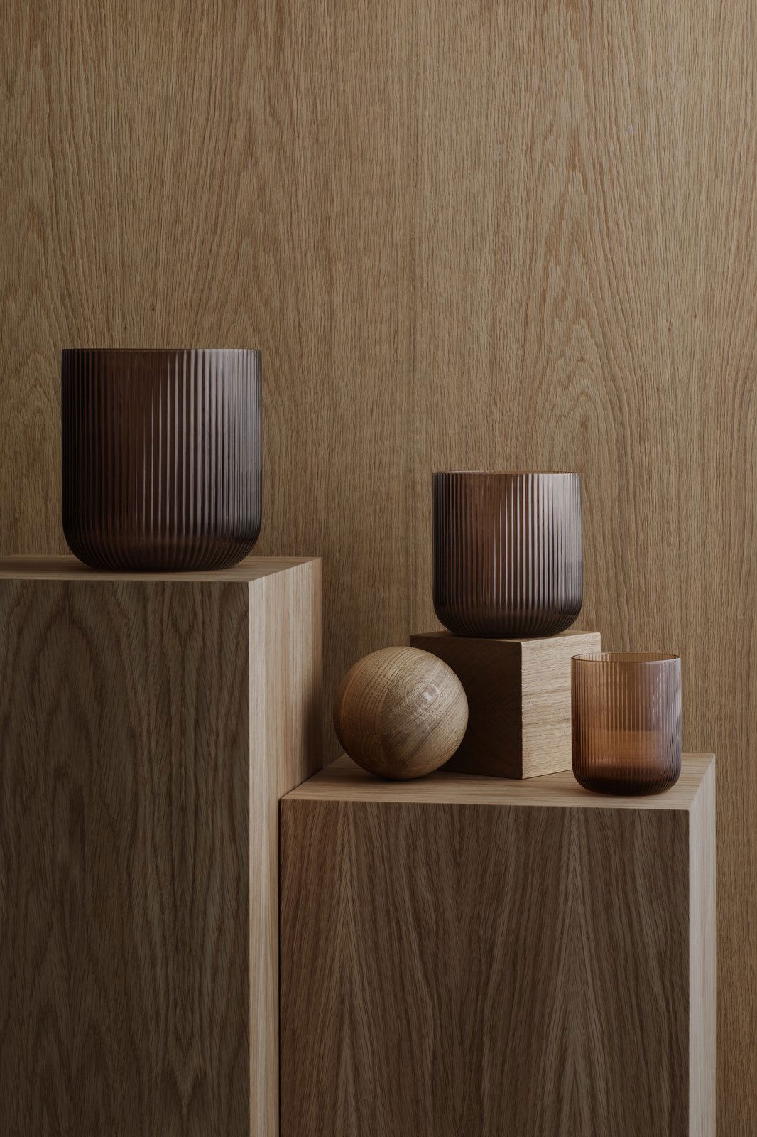 Stylish brown glass vases and wooden spheres on textured wooden blocks.