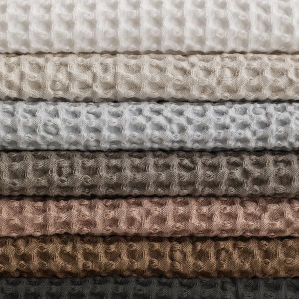 Textured fabric swatches in a gradient of neutral colors stacked neatly on top of each other.