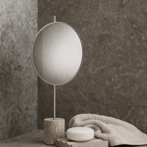 Stylish round mirror on a modern stone countertop with soft towel and soap.