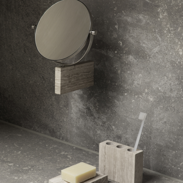 Minimalist bathroom setup with a circular mirror, soap, and toothbrush holder on stone surfaces.
