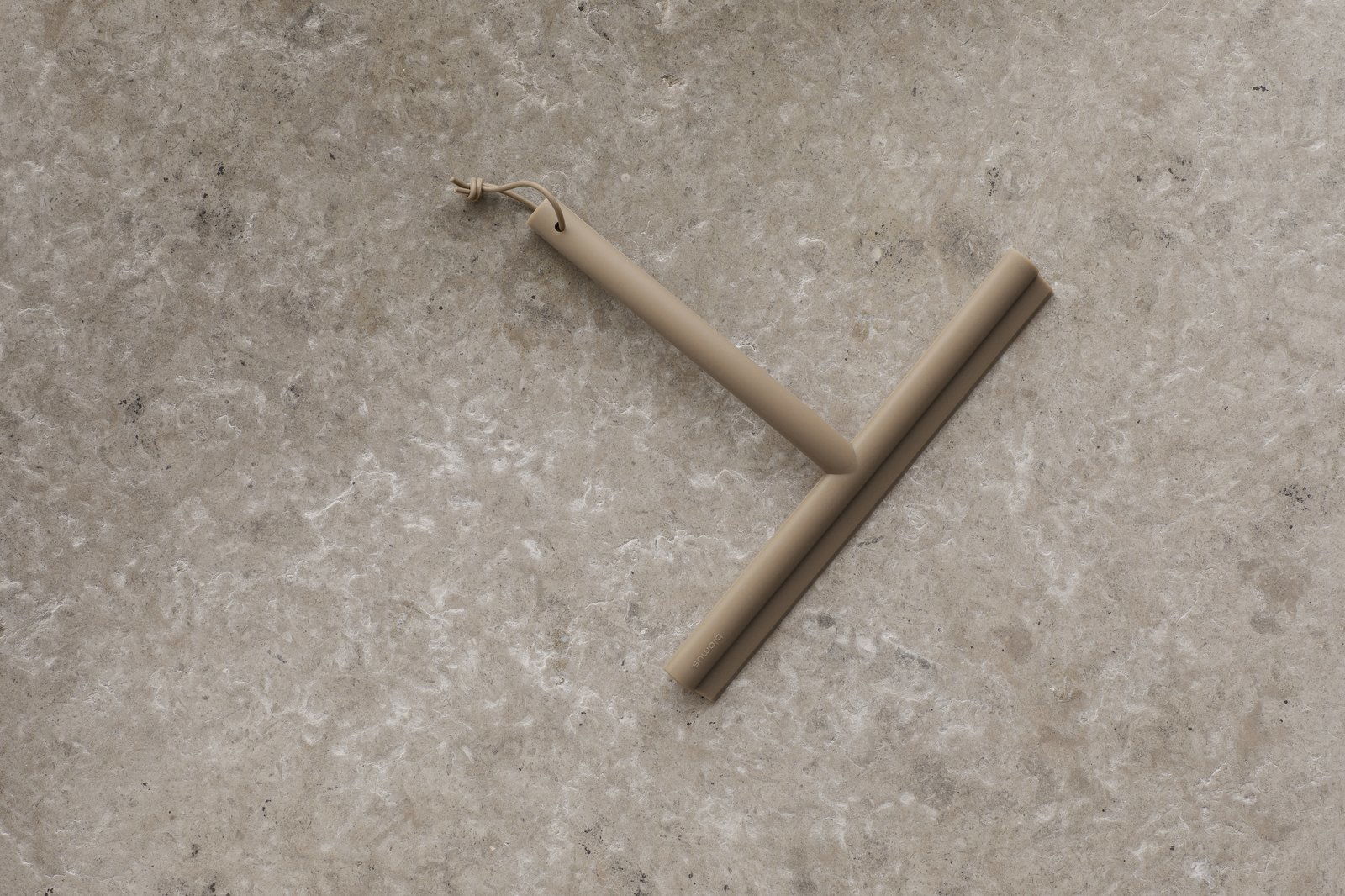 Minimalist beiger Abzieher auf einer strukturierten Steinoberfläche zum Reinigen und für die Wohnkultur.