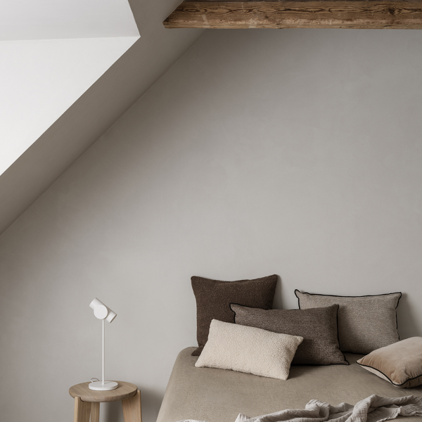 Gemütliches Schlafzimmer mit strukturierten Kissen und minimalistischem Dekor unter einer schrägen Decke.