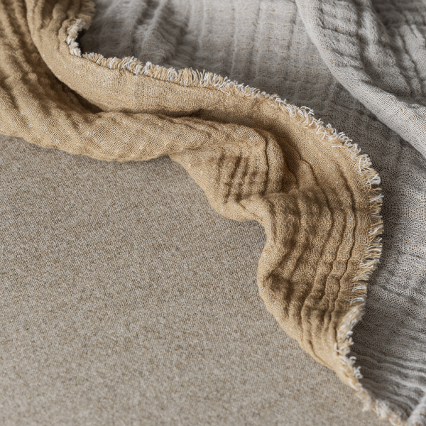 Soft, textured fabric draped elegantly in neutral tones on a light background.