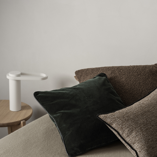 Gemütliche Schlafzimmer-Szene mit dekorativen Kissen und einer modernen Nachttischlampe.