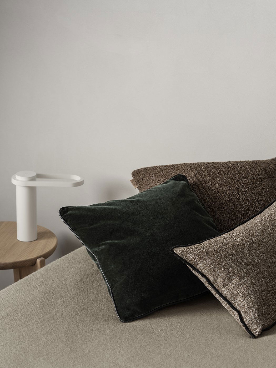 Gemütliche Schlafzimmer-Szene mit dekorativen Kissen und einer modernen Nachttischlampe.