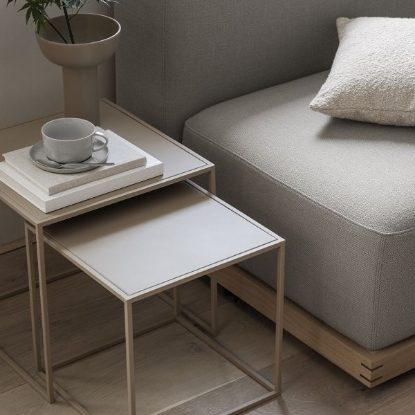 Moderne Wohnzimmergestaltung mit einem grauen Sofa, Beistelltischen und einer gemütlichen Tasse Kaffee.