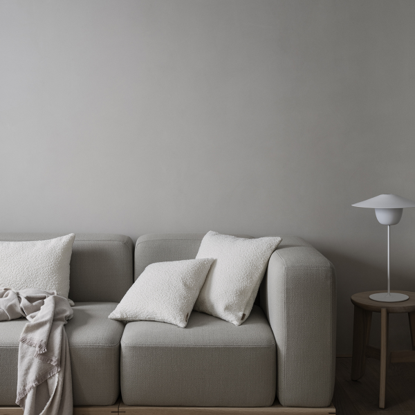 Gemütliches modernes Wohnzimmer mit einem grauen Sofa, dekorativen Kissen und einer minimalistischen Lampe.