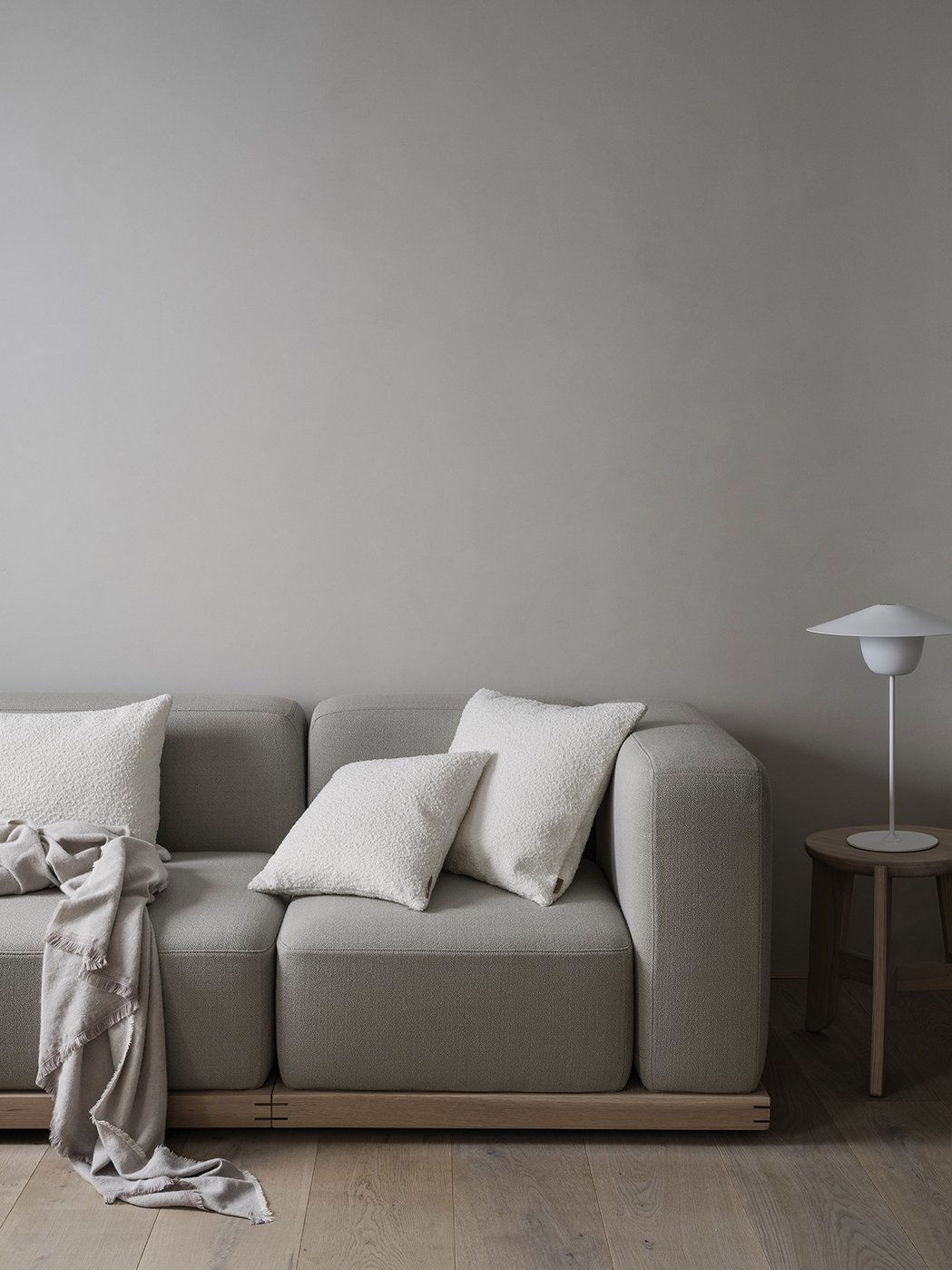 Gemütliches modernes Wohnzimmer mit einem grauen Sofa, dekorativen Kissen und einer minimalistischen Lampe.