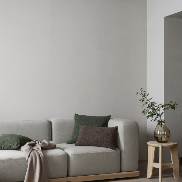 Moderner Wohnraum mit einem grauen Sofa, dekorativen Kissen und einem eleganten Beistelltisch.