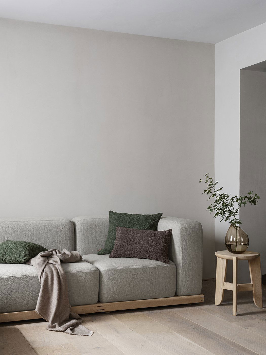 Moderner Wohnraum mit einem grauen Sofa, dekorativen Kissen und einem eleganten Beistelltisch.