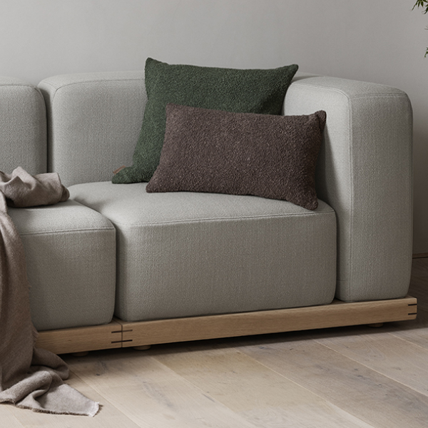 Moderner grauer Sofa mit strukturierten Kissen und einer gemütlichen Decke.