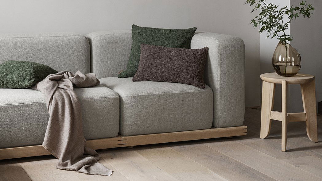 Moderner grauer Sofa mit strukturierten Kissen und einer gemütlichen Decke.