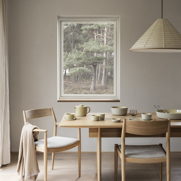 Cozy dining area with wooden furniture and a serene forest view through a window.