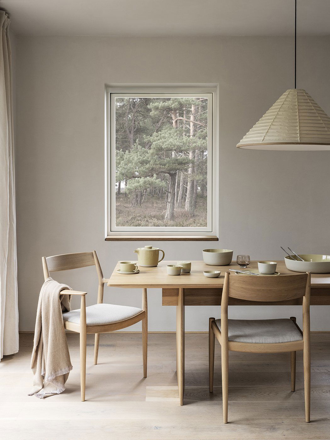 Cozy dining area with wooden furniture and a serene forest view through a window.
