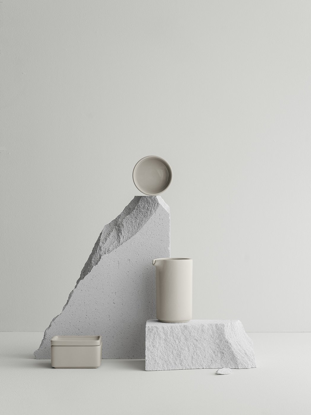 Minimalistisches Keramiktischgeschirr, das auf strukturiertem grauem Stein mit einem sanften Hintergrund präsentiert wird.