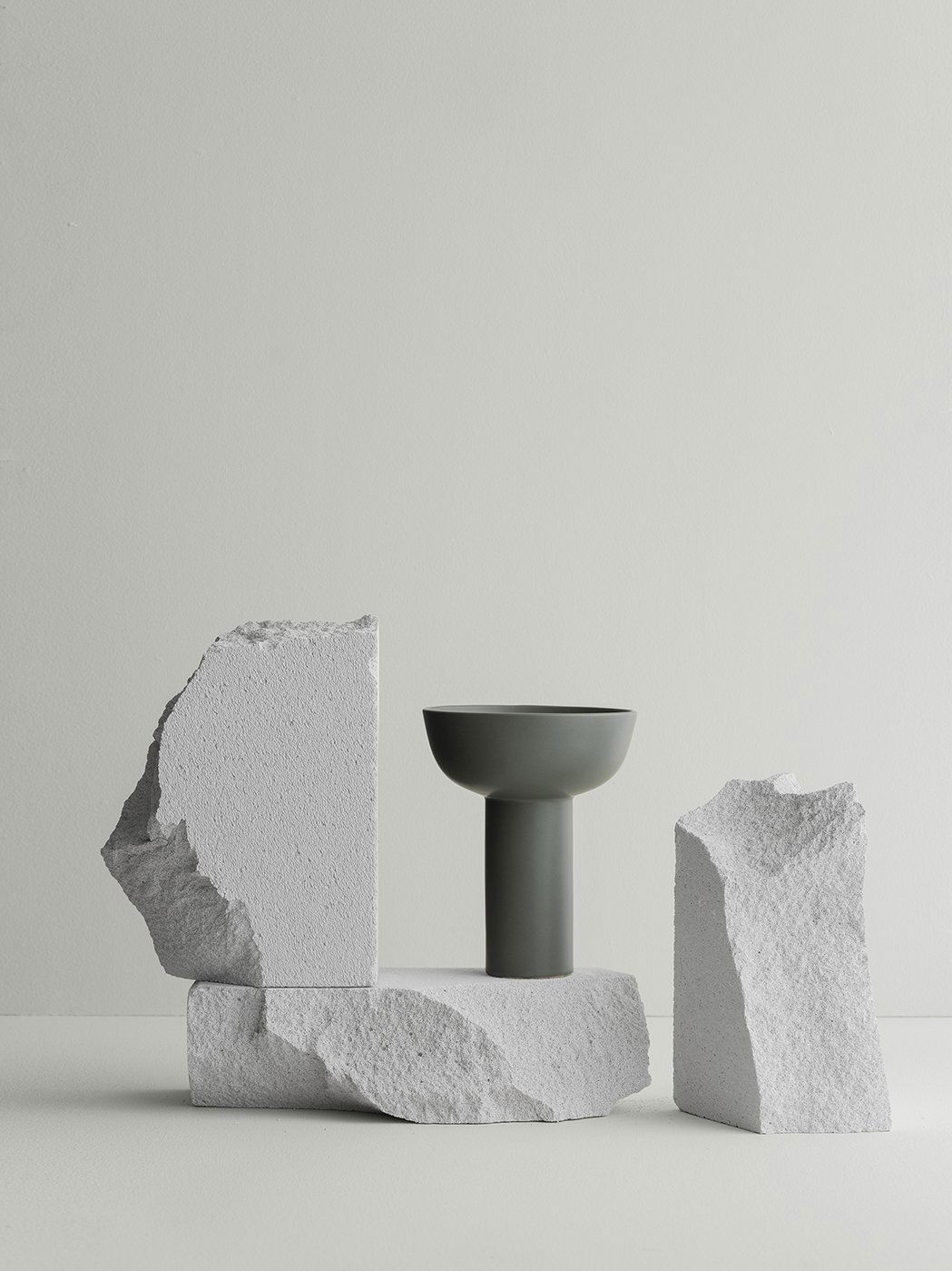 Minimalistische Vase auf strukturiertem Steindisplay vor einem hellen Hintergrund.