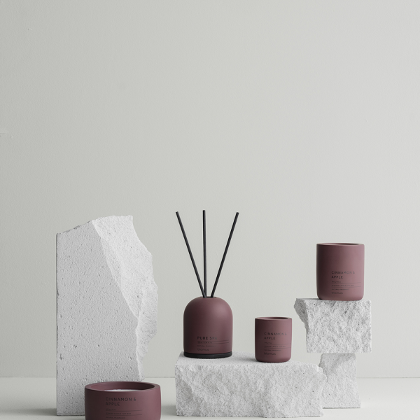 Stylish home fragrance display with diffusers and candles on textured stone pedestal.