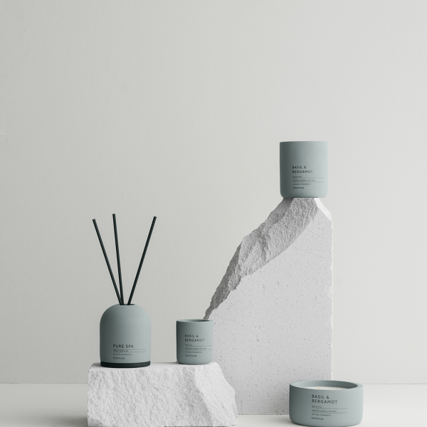 Elegant collection of scented candles and diffusers on minimalist stone display.