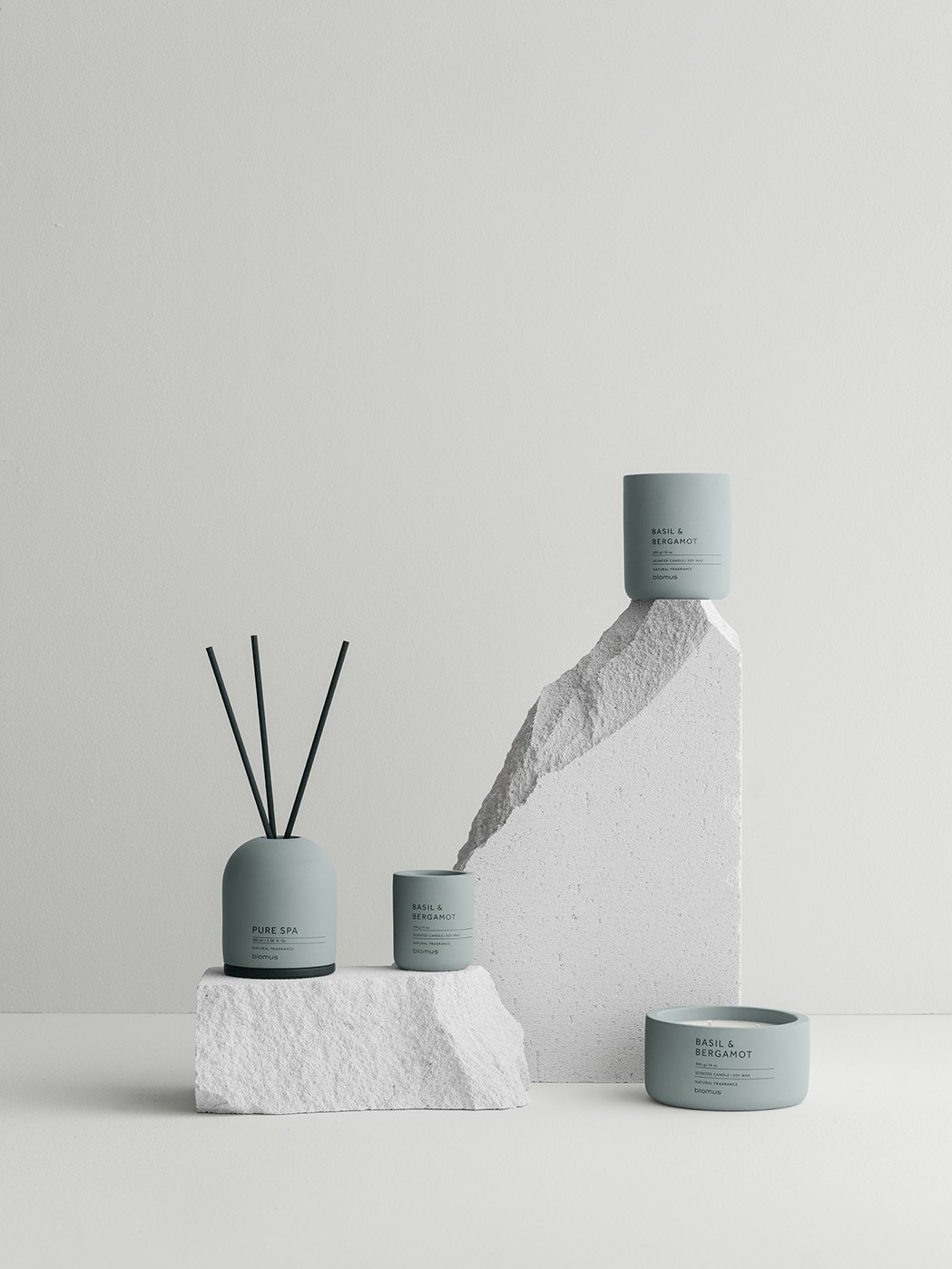 Elegant collection of scented candles and diffusers on minimalist stone display.