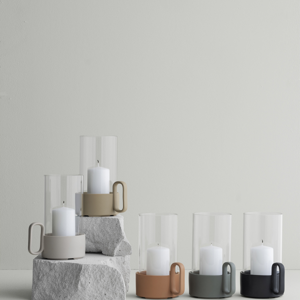 Elegante Glaskerzenhalter mit minimalistischen Designs und neutralen Farben auf einem Steinfuss.