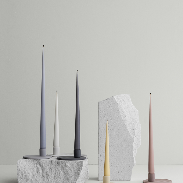 Modern candle holders in minimalist design, featuring various colors and textures on a light backdrop.
