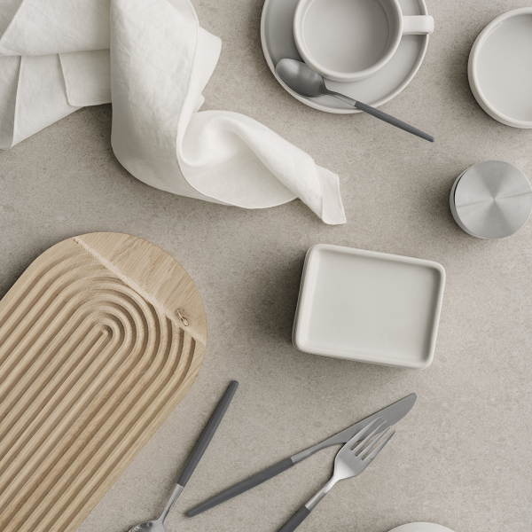 Minimalistische Tischdekoration mit grauem Geschirr und einem Holzserviertablett.