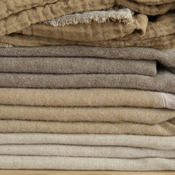 Stacked fabrics in neutral tones showcasing different textures and layers.