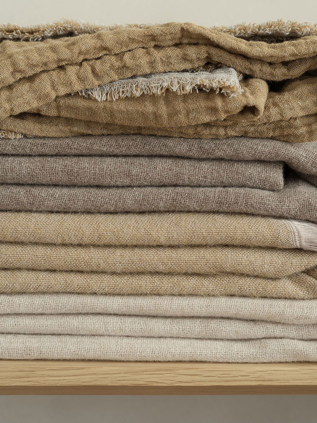 Stacked fabrics in neutral tones showcasing different textures and layers.