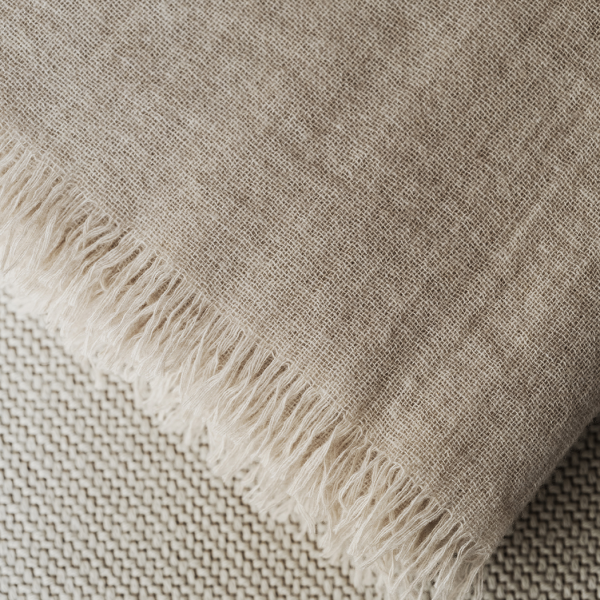 Natural linen fabric with frayed edges, showcasing a soft, textured surface.