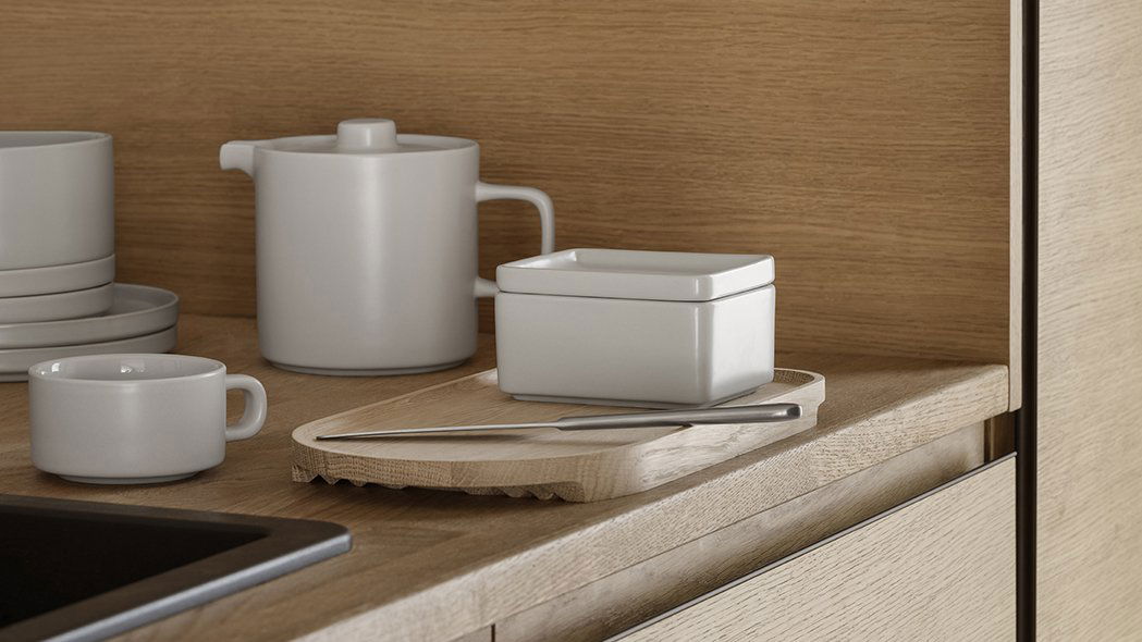 Moderne Küchenarbeitsplatte mit minimalistischem Geschirr und einem Holzservierteller.
