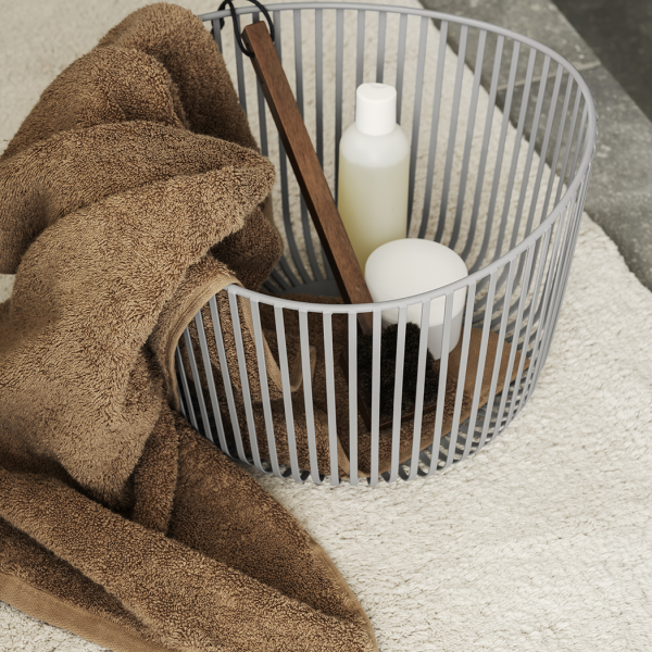 Neutrale Badezimmerdekoration mit Handtüchern, einem Korb und Toilettenartikeln auf einem weichen Teppich.