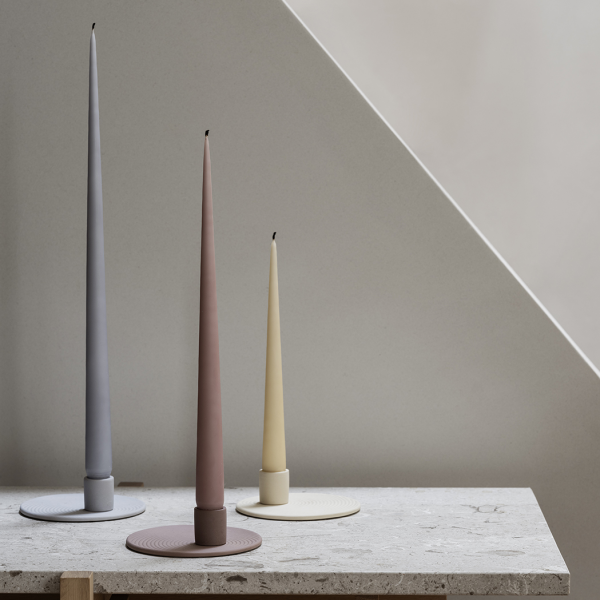 Elegant tapered candles in pastel colors displayed on a minimalist stone surface.