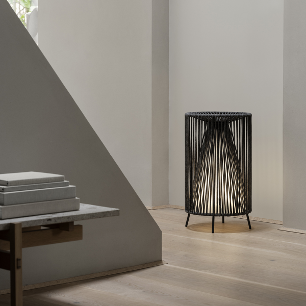 Moderne schwarze Drahtlampe, die einen minimalistischen Innenraum mit Holzfußboden beleuchtet.