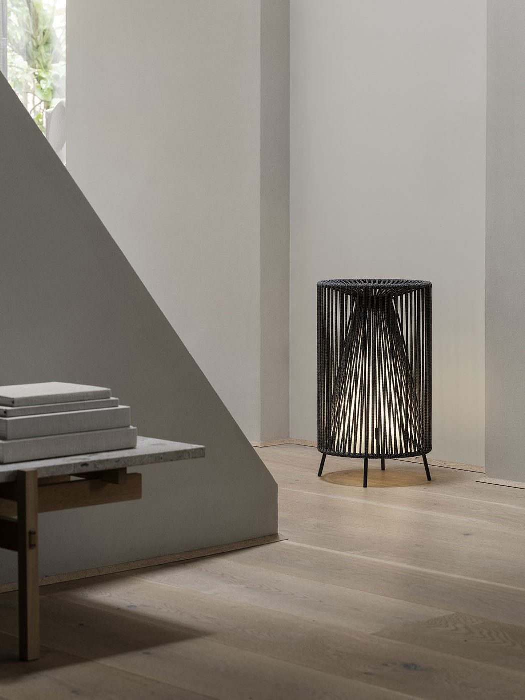 Moderne schwarze Drahtlampe, die einen minimalistischen Innenraum mit Holzfußboden beleuchtet.