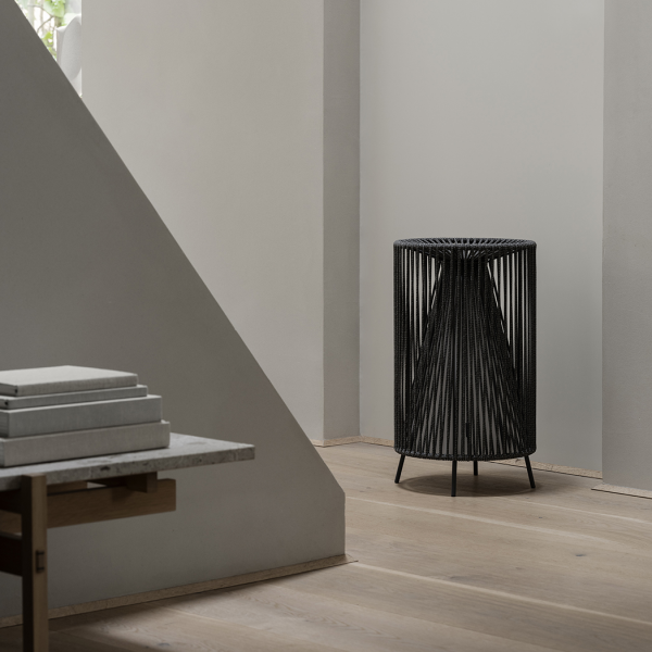 Stylischer schwarzer Drahtblumentopf neben einem minimalistischen Holztisch in einem modernen Interior.
