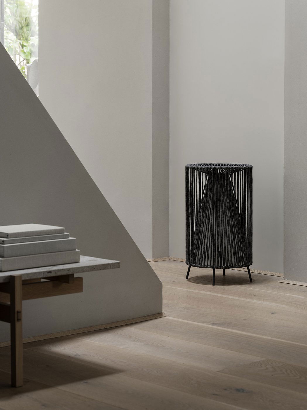 Stylischer schwarzer Drahtblumentopf neben einem minimalistischen Holztisch in einem modernen Interior.