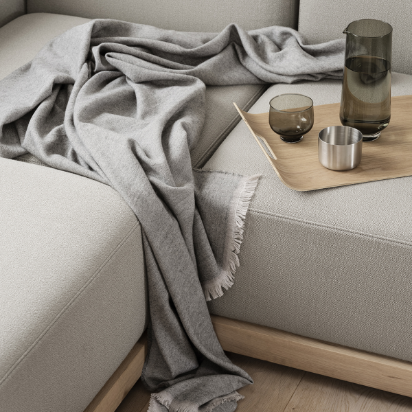 Gemütliche graue Decke über einem modernen Sofa mit eleganten Gläsern und einem Holztablett drapiert.