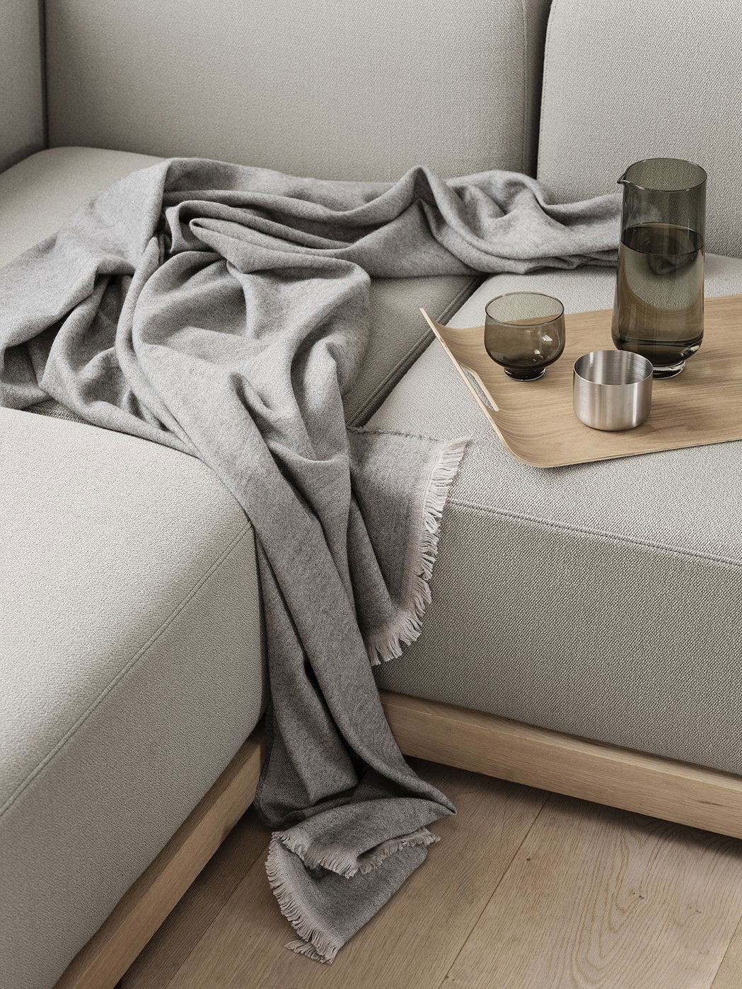 Gemütliche graue Decke über einem modernen Sofa mit eleganten Gläsern und einem Holztablett drapiert.