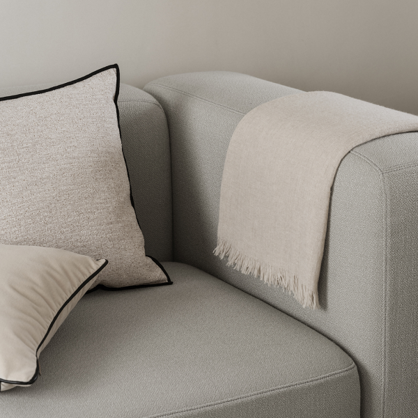 Gemütlicher Sofaecke mit strukturierten Kissen und einer weichen beige Decke.