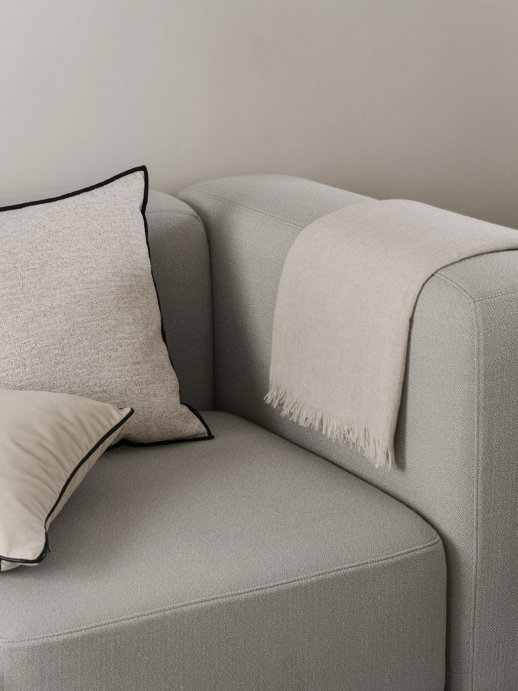 Gemütlicher Sofaecke mit strukturierten Kissen und einer weichen beige Decke.