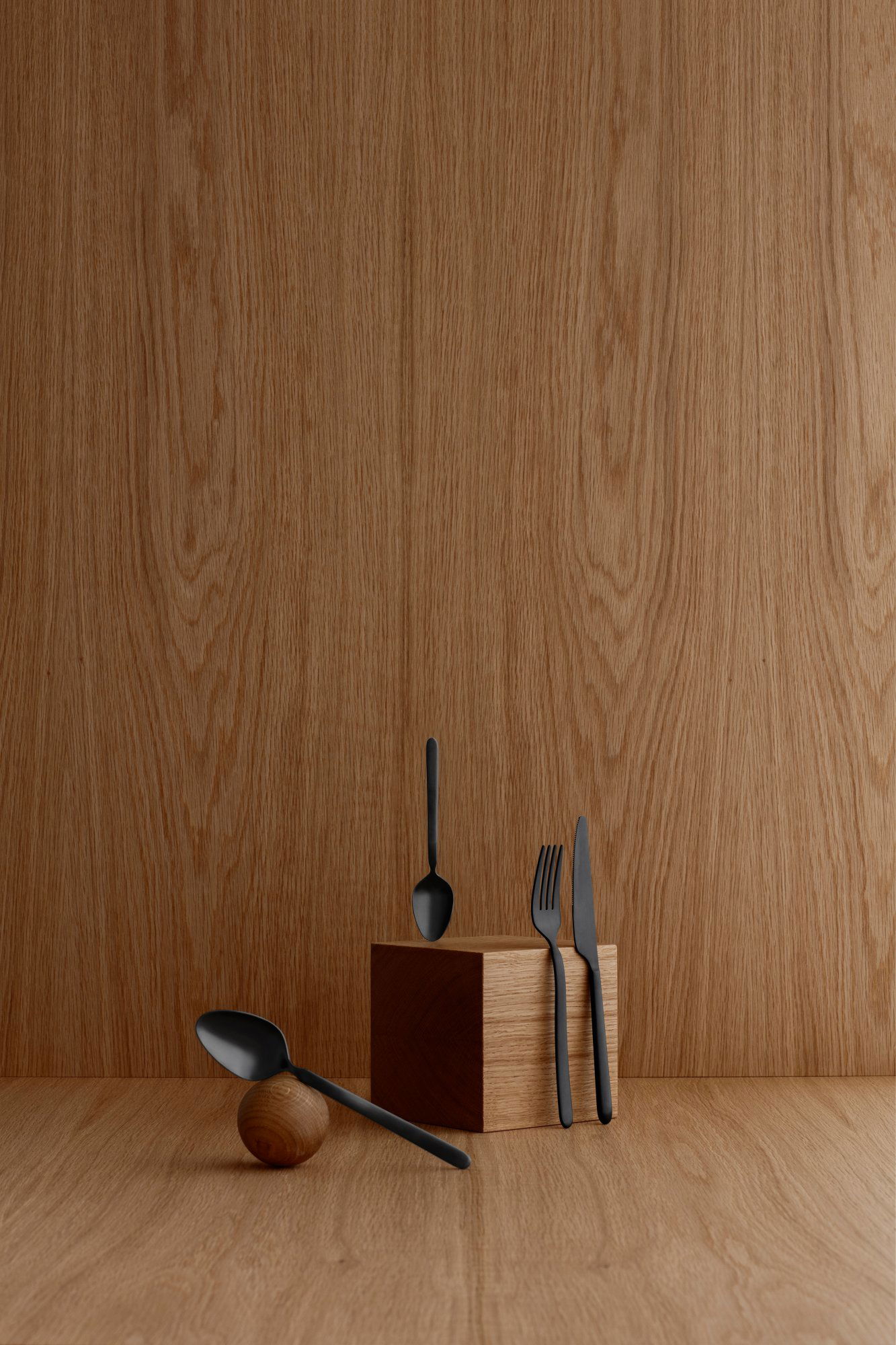 Black cutlery displayed on a wooden surface, highlighting modern tableware design.