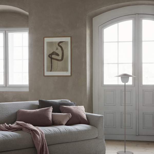 Cozy living room with a modern artwork, soft pillows, and natural light from large windows.