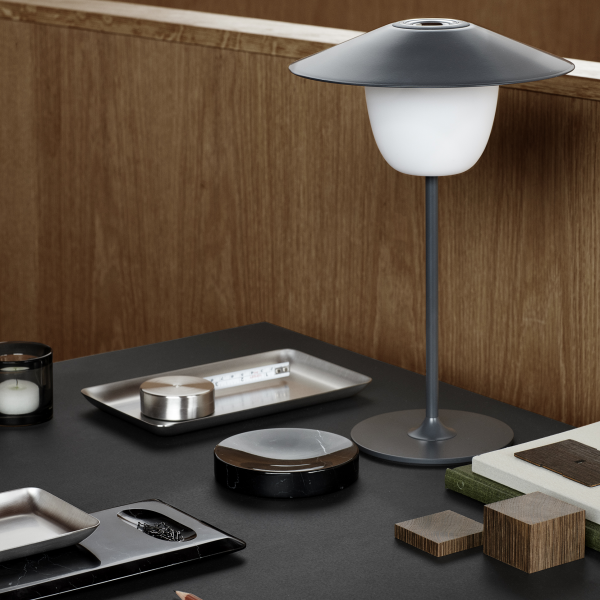 Stilvolle moderne Lampe auf einem Holztisch mit elegantem Geschirr und dekorativen Gegenständen.